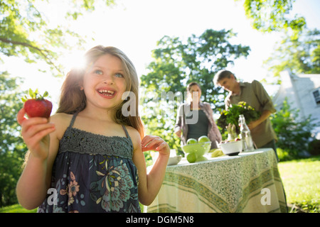 In azienda i figli adulti insieme ragazza giovane azienda grandi organicamente fresche prodotte fragole due adulti accanto a turno Foto Stock