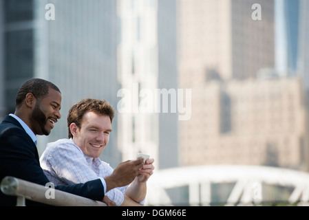 L'estate. Due uomini guardando uno smart phone, SMS e messaggistica foto. Foto Stock