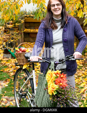 Una donna con le mele e le biciclette in giardino Foto Stock