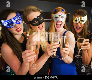 Attraente amici con le maschere sulla detenzione di bicchieri di champagne Foto Stock