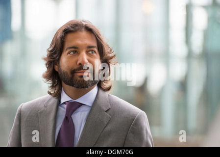 La gente di affari fuori e circa nella città. Un Latino uomo in un abito giacca e cravatta viola. Foto Stock