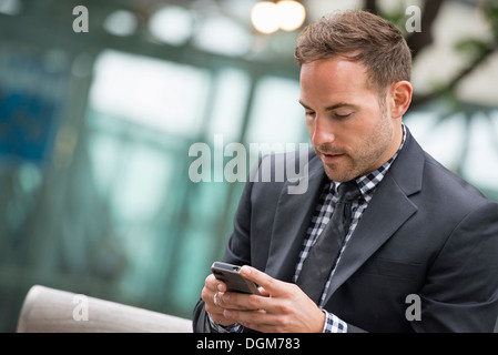 La gente di affari. Un uomo in un business suit. Un uomo con corti capelli rossi e la barba, indossa una tuta, sul suo telefono cellulare. Foto Stock