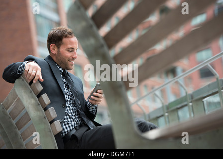 La gente di affari. Un uomo in una tuta, seduta su una panchina. Foto Stock