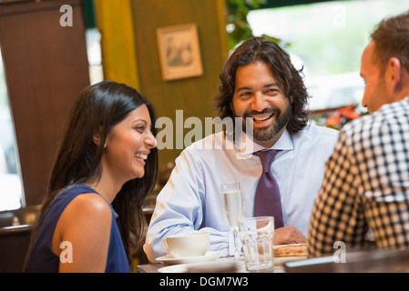 La gente di affari. Tre persone sedute intorno ad un tavolo in un bar o caffè, avente le bevande. Foto Stock