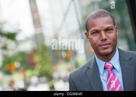 Un giovane uomo in un business vestito con una camicia blu e cravatta rossa Su una strada di città.