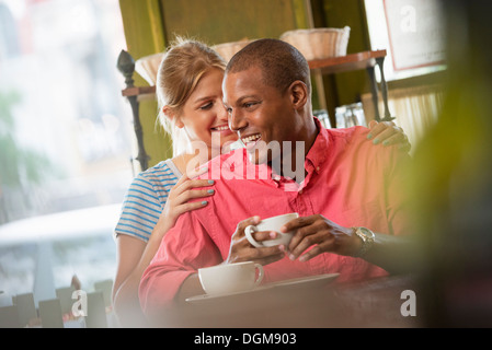 Due persone, un uomo e una donna seduta vicino insieme, guardando ogni altro. Avere una tazza di caffè. Foto Stock