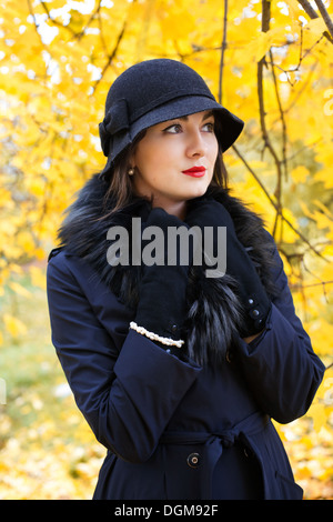 La donna in un cappello nero su sfondo di autumn tree Foto Stock