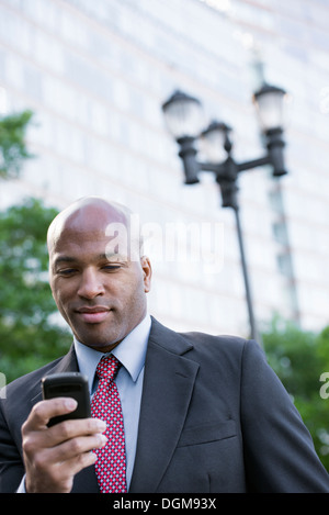 La gente di affari. Un uomo in una tuta controllando il suo telefono. Foto Stock