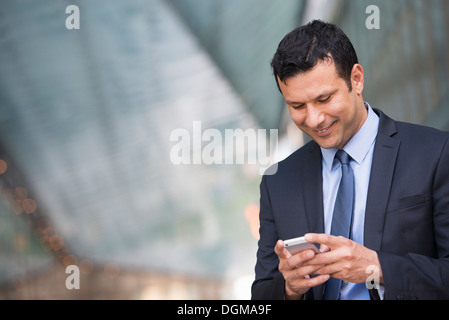 La gente di affari. Un latino imprenditore nel business vestiti. Utilizzando il suo telefono. Foto Stock