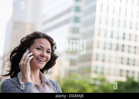 La gente di affari. Una imprenditrice in una leggera giacca grigia, utilizzando il suo smart phone. Foto Stock