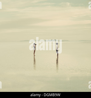 L uomo e la donna in piedi sul allagato Bonneville Saline, scattare fotografie di ogni altra al tramonto. Foto Stock