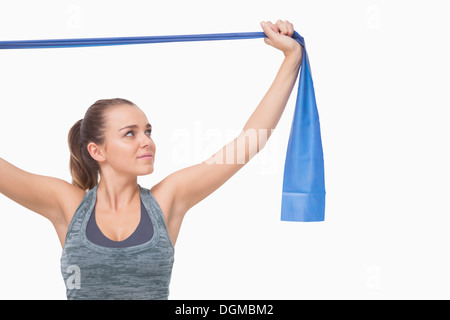 Ponytailed giovane donna formazione utilizzando una banda di resistenza Foto Stock