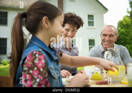 Un estate incontro di famiglia in una fattoria. Un gruppo di famiglia, genitori e figli. Fare limonata fresca. Foto Stock