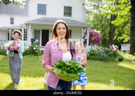 Festa di famiglia. I genitori e i bambini che trasportano fiori freschi raccolti di frutta e verdura. Per preparare a parte. Foto Stock