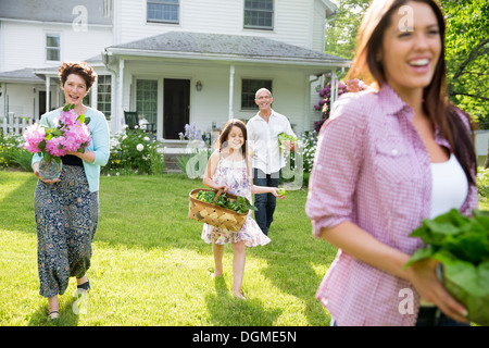 Festa di famiglia. I genitori e i bambini che trasportano fiori freschi raccolti di frutta e verdura. Per preparare a parte. Foto Stock