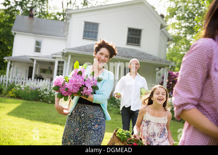 Festa di famiglia. I genitori e i bambini che trasportano fiori freschi raccolti di frutta e verdura. Per preparare a parte. Foto Stock