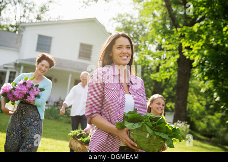 Festa di famiglia. I genitori e i bambini che trasportano fiori freschi raccolti di frutta e verdura. Per preparare a parte. Foto Stock