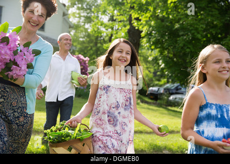 Festa di famiglia. I genitori e i bambini che trasportano fiori freschi raccolti di frutta e verdura. Per preparare a parte. Foto Stock