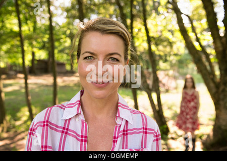 Una madre e figlia all'ombra di alberi fuori in estate. Foto Stock