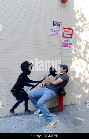 La città di New York, Stati Uniti d'America. Xx oct, 2013. I Newyorkesi e turisti fotografare sé davanti ad un'opera raffigurante una silhouette di un martello ragazzo giocando 'strong man" nell' Upper West Side. La stampata in graffiti è stato creato da British Graffiti artist Banksy come parte del suo "Meglio fuori rispetto all' esposizione ny su ottobre 20, 2013 a New York City, Stati Uniti d'America. © dpa/Alamy Live News Foto Stock