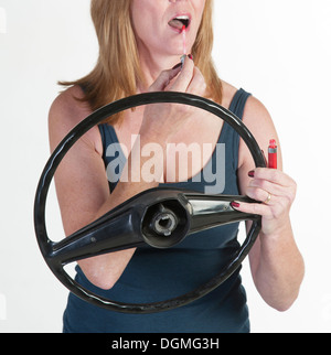 Automobilista di sesso femminile di applicare il make up al volante e non indossare una cintura di sicurezza Foto Stock
