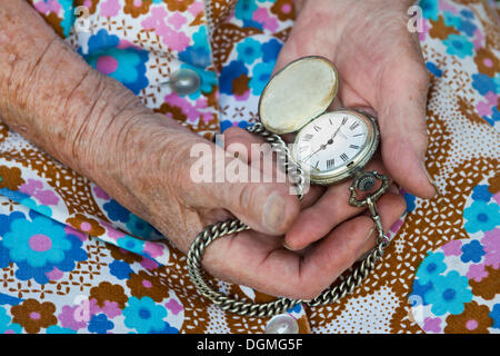 Donna anziana in possesso di un vecchio orologio da tasca nelle sue mani Foto Stock