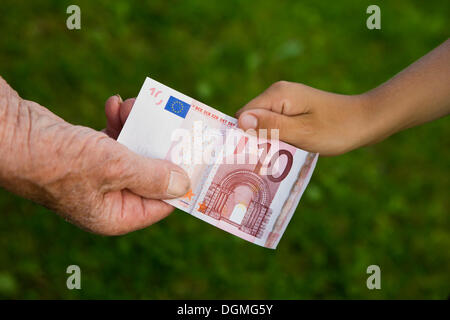 Donna anziana e un bambino tirando su dieci di banconote in euro Foto Stock