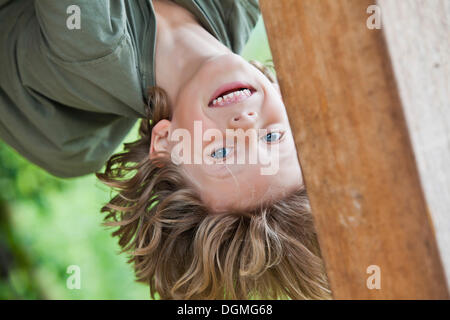 Il ragazzo, 6, arrampicata, appeso a testa in giù Foto Stock