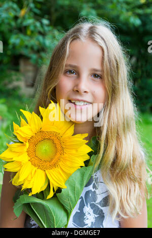 Ragazza, 9, ritratto tenendo un girasole Foto Stock