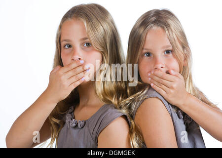 Due gemelle, 9, tenendo la bocca chiusa Foto Stock