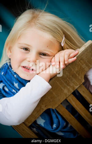 Ragazza 4 anni con la testa appoggiata su una sedia Foto Stock