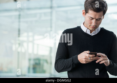 Estate in città. La gente di affari in abiti casual. Un giovane uomo di controllare il suo smart phone. Foto Stock
