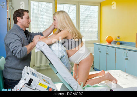 L uomo e la donna nella sala parto durante il parto, la donna in ginocchio sul letto di consegna e di riposo, essa è collegata a un Foto Stock