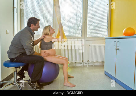 L uomo e la donna nella sala parto durante il parto, la donna è seduta su una sfera durante il travaglio, Germania Foto Stock