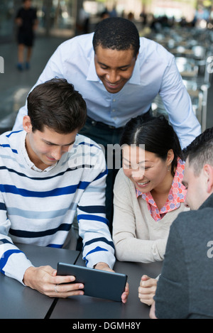 La gente di affari in movimento. Quattro persone raccolte intorno a una tavoletta digitale avente una discussione. Vista aerea. Foto Stock