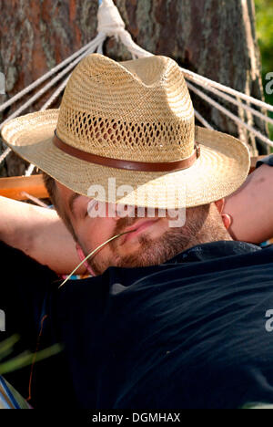 Uomo dorme in un'amaca con un cappello sul suo volto Foto Stock