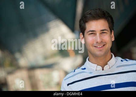 La gente di affari in movimento. Un giovane uomo in un maglione a righe guardando la telecamera. Foto Stock