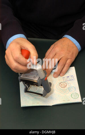 Le mani con un timbro in un controllo passaporti Foto Stock
