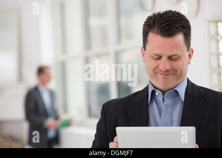 La gente di affari. Un uomo in abito scuro utilizzando un tavolo digitale. Foto Stock