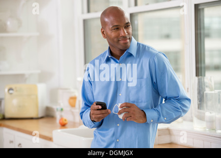 La gente di affari. Un uomo con la maglietta blu con uno smart phone in mano. Foto Stock