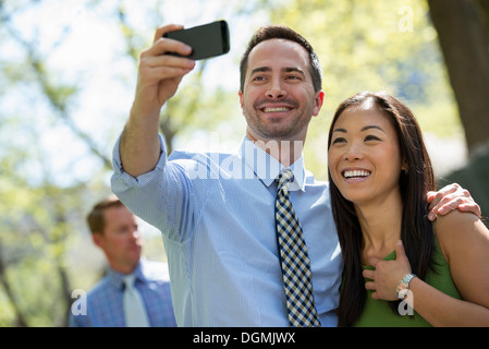 Un giovane con uno smart phone, fianco a fianco. Un uomo in background. Foto Stock