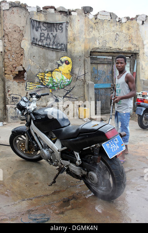 Ragazzo di lavaggio di un moto con un tubo flessibile a getto Foto Stock