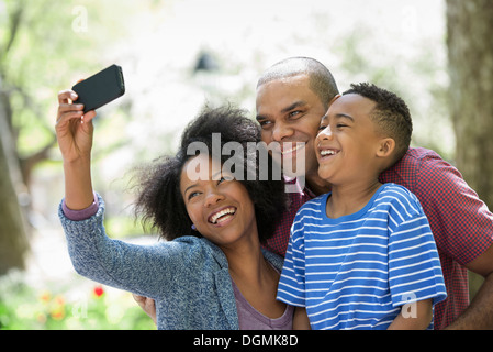 Due adulti e un ragazzino scattare fotografie con un telefono intelligente. Foto Stock