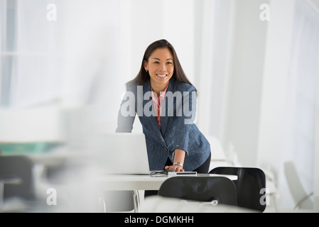 Business. Una donna appoggiata su una scrivania utilizzando un computer portatile. Foto Stock