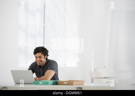 Business. Un uomo seduto a una scrivania con un computer portatile. Foto Stock