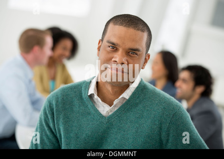 Riunione di affari. Un gruppo di sedersi intorno a un tavolo. Un uomo sorridente con fiducia. Foto Stock