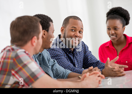 Ufficio. Un gruppo di quattro persone, due uomini e due donne seduti a parlare. Foto Stock
