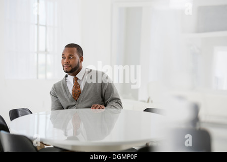 Ufficio interno. Un uomo in un business suit a un tavolo seduti ad un tavolo. Foto Stock