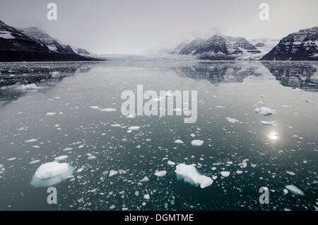 Iceberg nella parte anteriore del cloud velati di montagna e lo scenario del ghiacciaio, Vikingebugt, Scoresbysund, Sermersooq, Groenlandia Foto Stock