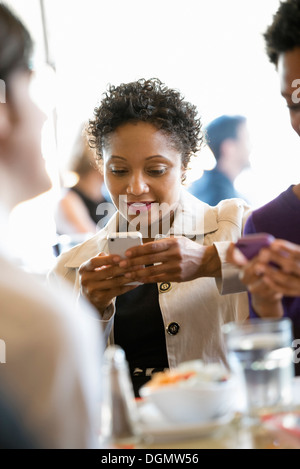 La vita della città. Un gruppo di persone in un café, controllando la loro smart phone. Foto Stock